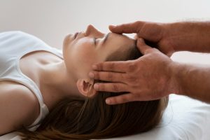woman lying down while being head massaged